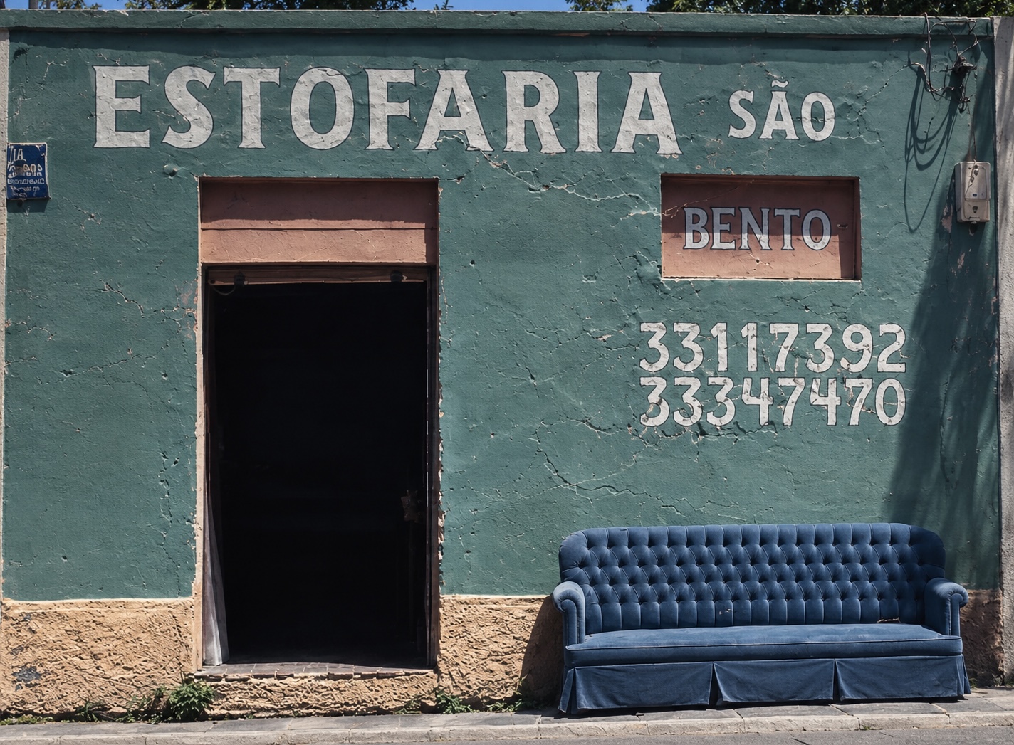 Fachada antiga da Estofaria São Bento com sofá azul capitonê